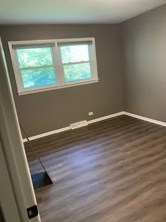 an empty room with wooden floor and a bathroom