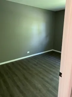 a living room with stainless steel appliances furniture refrigerator and a wooden floor