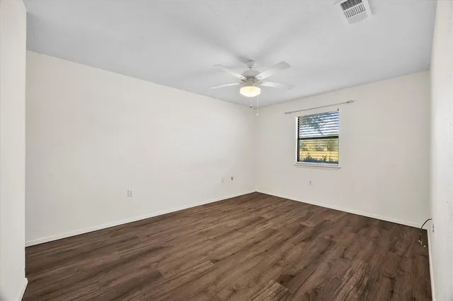 an empty room with wooden floor and window