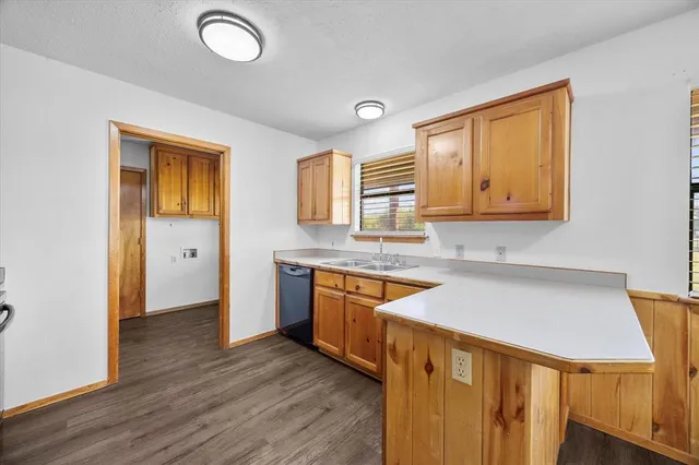 a kitchen with stainless steel appliances granite countertop a sink and wooden cabinets with wooden floors