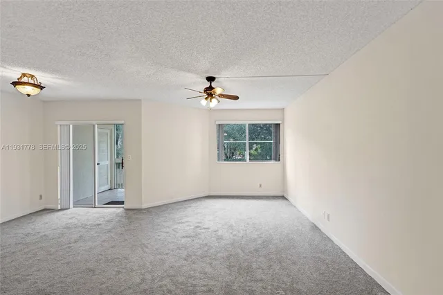 an empty room with windows and a ceiling fan
