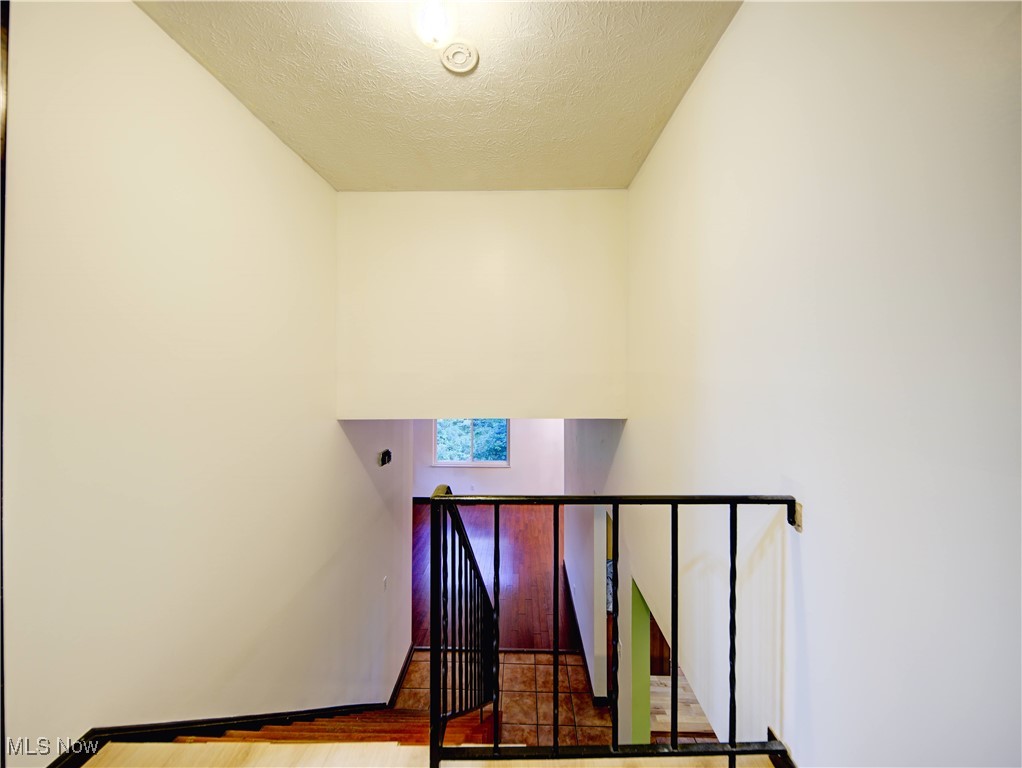8075 Mulberry Road Chesterland, OH 44026 - Photo 32 of 38 Stairs with a textured ceiling, tile patterned flooring, and a towering ceiling