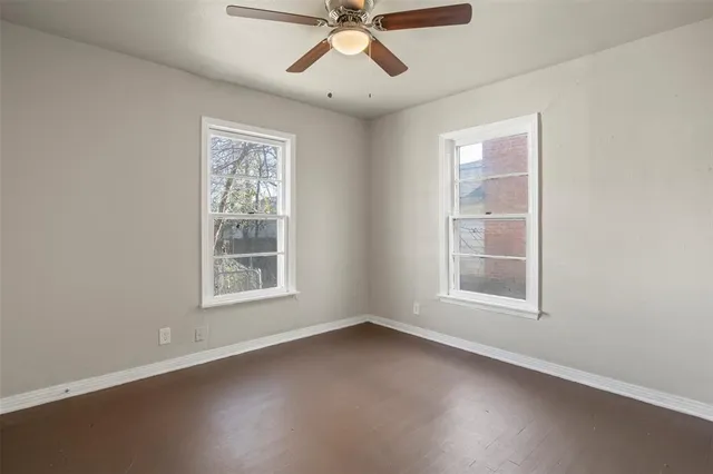 an empty room with chandelier fan and windows