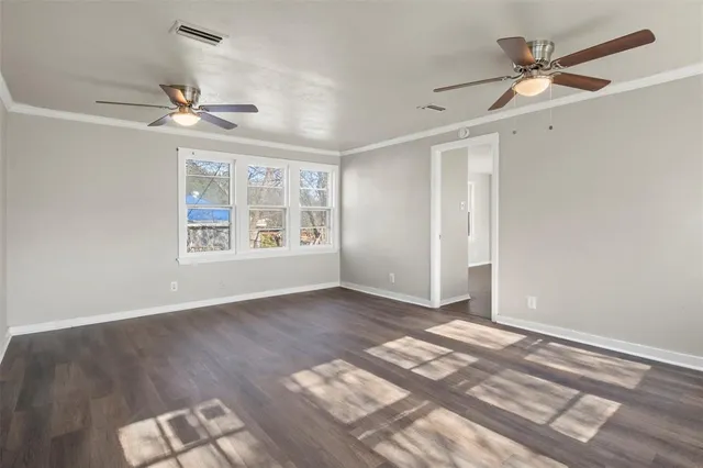 an empty room with wooden floor ceiling fan and windows