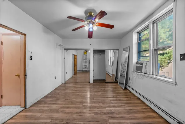 a view of an empty room with wooden floor and a window