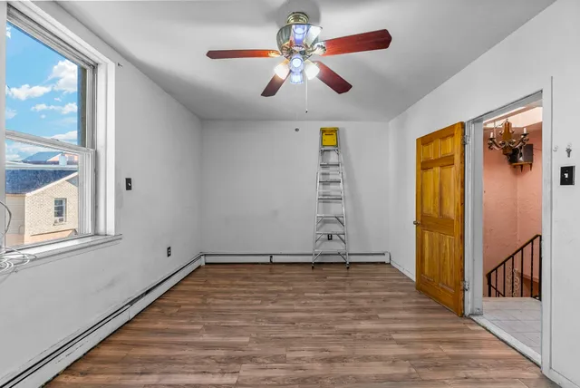 a view of an empty room with window and wooden floor