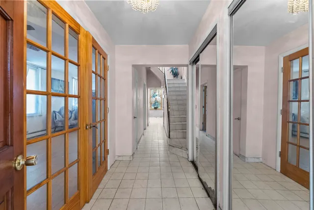 a hallway with wooden floor chandelier and entryway