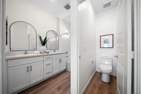 a bathroom with a double vanity sink and mirror with bathtub