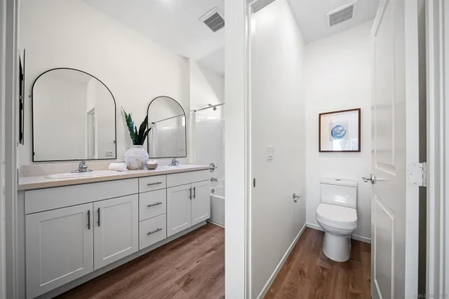 a bathroom with a double vanity sink and mirror with bathtub