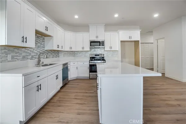 a large kitchen with stainless steel appliances kitchen island granite countertop a stove a sink a refrigerator and a granite counter tops with wooden floors