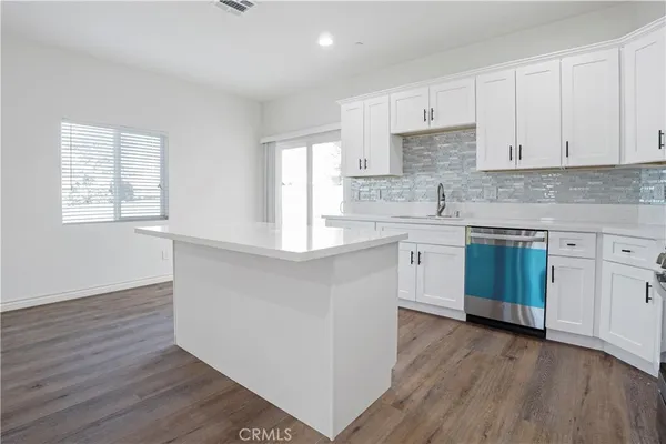 a kitchen with a white cabinets sink and dishwasher with wooden floor
