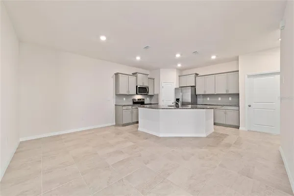 a large white kitchen with kitchen island a sink a center island stainless steel appliances and a refrigerator
