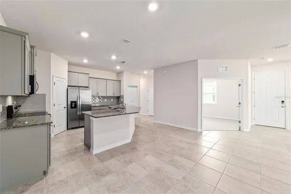 a kitchen with kitchen island granite countertop a stove a sink and a refrigerator
