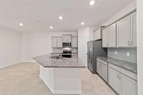 a kitchen with stainless steel appliances granite countertop a sink refrigerator and cabinets