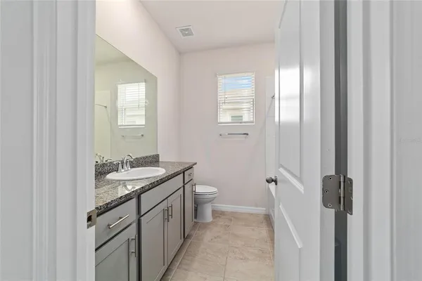 a spacious bathroom with a granite countertop sink a toilet and a mirror