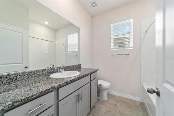 a bathroom with a granite countertop sink a toilet and a mirror