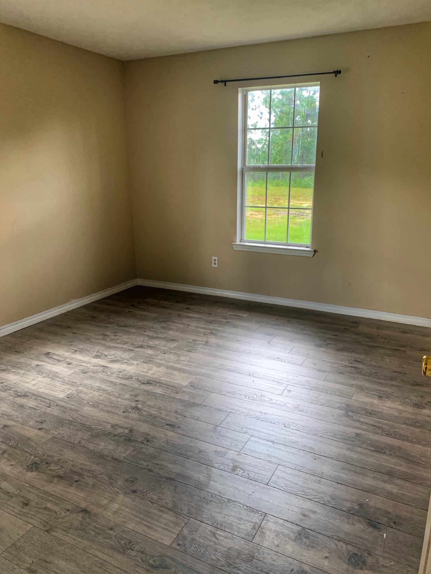 657 Elmwood Road DeFuniak Springs, FL 32433 - Photo 8 of 15 wooden floor in an empty room with a window