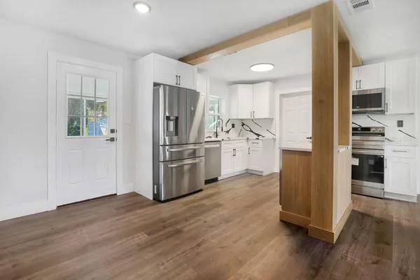 a kitchen with stainless steel appliances wooden floor and a refrigerator