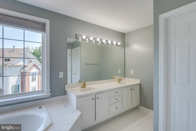 a spacious bathroom with a double vanity sink a large mirror and a bathtub