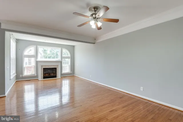 an empty room with fireplace chandelier fan and windows