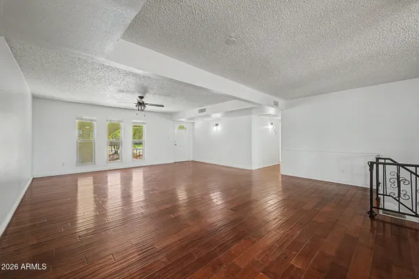 a view of empty room with wooden floor and ceiling fan