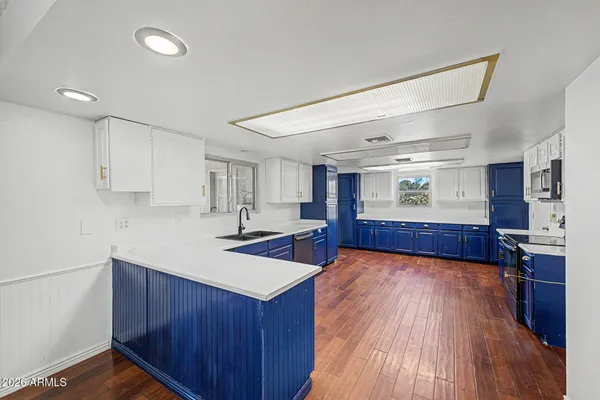 a kitchen with stainless steel appliances granite countertop a sink dishwasher stove and wooden cabinets with wooden floor