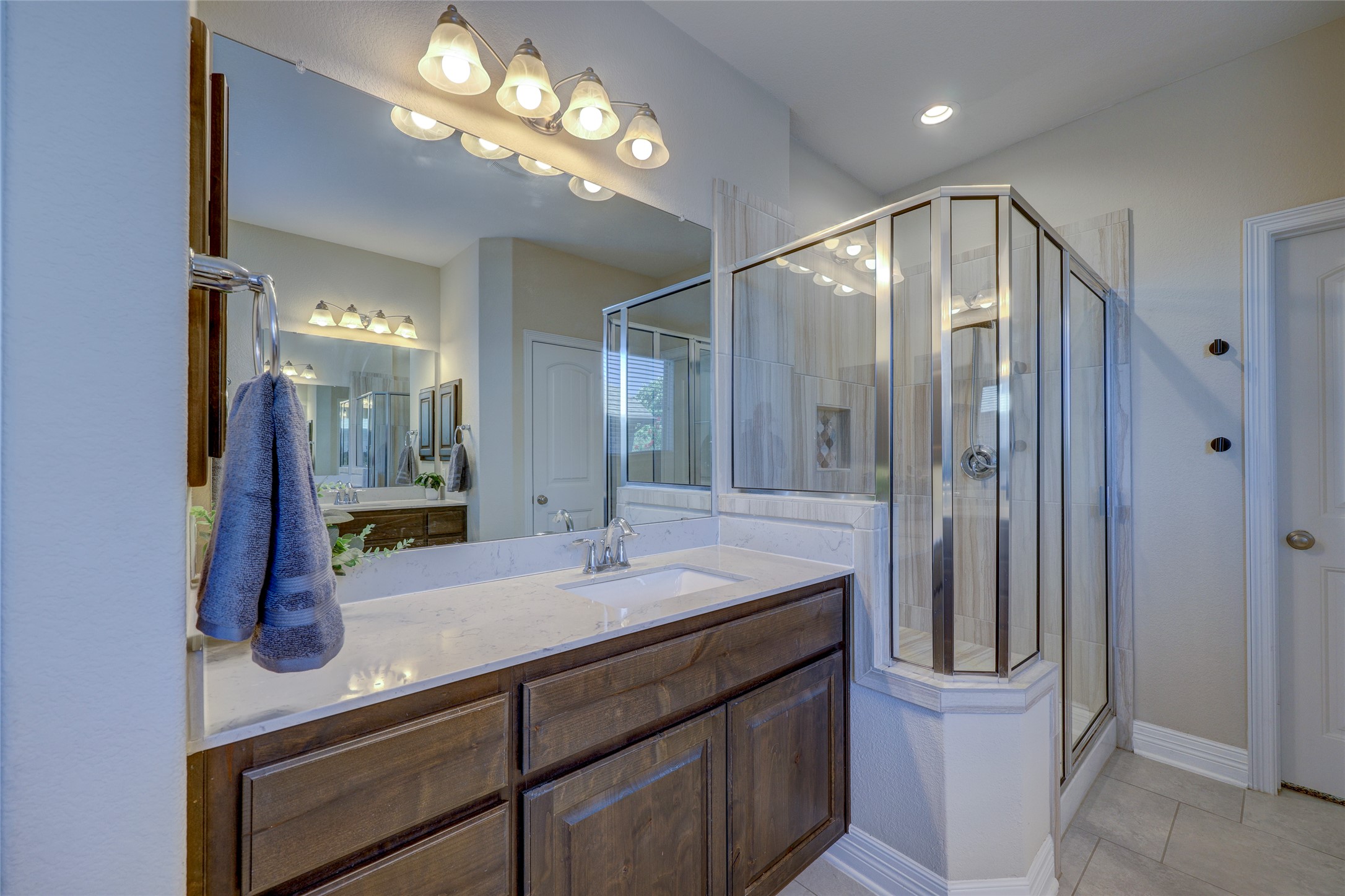409 Betony Loop Buda, TX 78610 - Photo 21 of 38 Clean lines and a functional design define this well-appointed primary bathroom, featuring a glass-enclosed shower and a vanity with ample counter space.