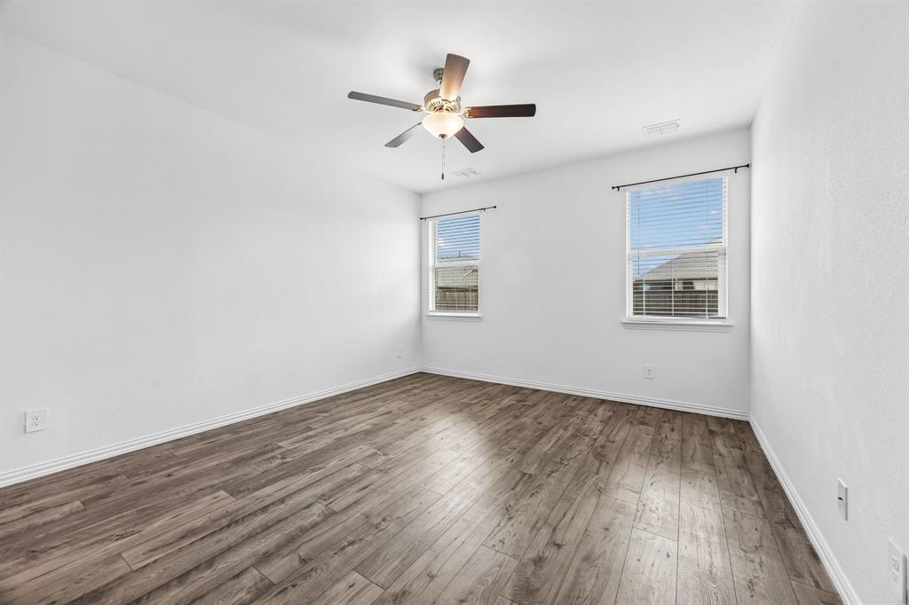 820 Carmen Street Forney, TX 75126 - Photo 12 of 25 a view of an empty room with wooden floor and a ceiling fan