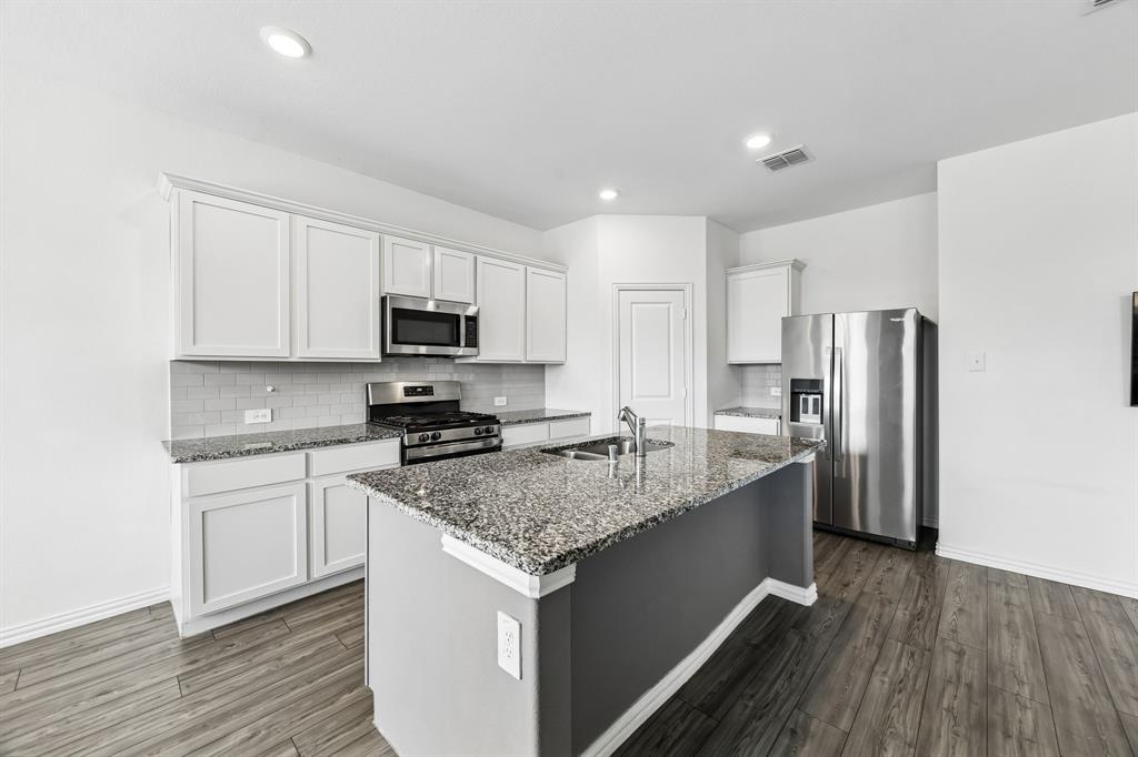 820 Carmen Street Forney, TX 75126 - Photo 7 of 25 a kitchen with stainless steel appliances granite countertop a sink stove microwave and refrigerator