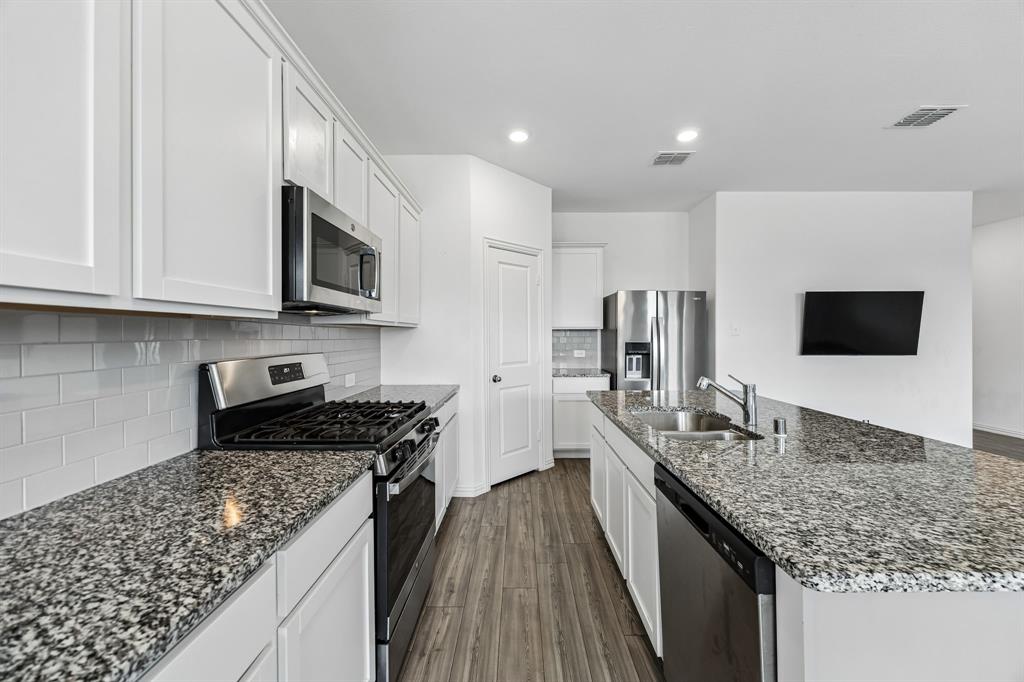 820 Carmen Street Forney, TX 75126 - Photo 8 of 25 a kitchen with stainless steel appliances granite countertop a sink stove microwave and refrigerator
