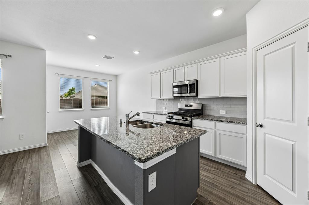820 Carmen Street Forney, TX 75126 - Photo 10 of 25 a kitchen with granite countertop stainless steel appliances sink stove microwave and cabinets