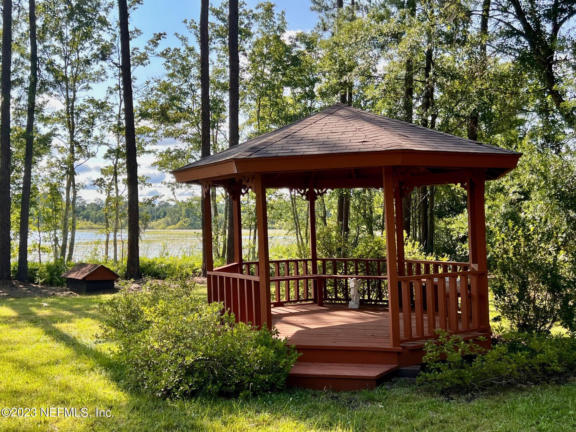 121 Peniel Church Road Palatka, FL 32177 - Photo 62 of 81 a view of a deck with a table and chairs under an umbrella with large trees