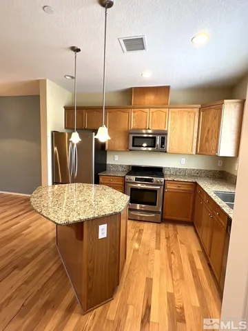 a kitchen with stainless steel appliances granite countertop a sink a stove top oven a chimney and a center island
