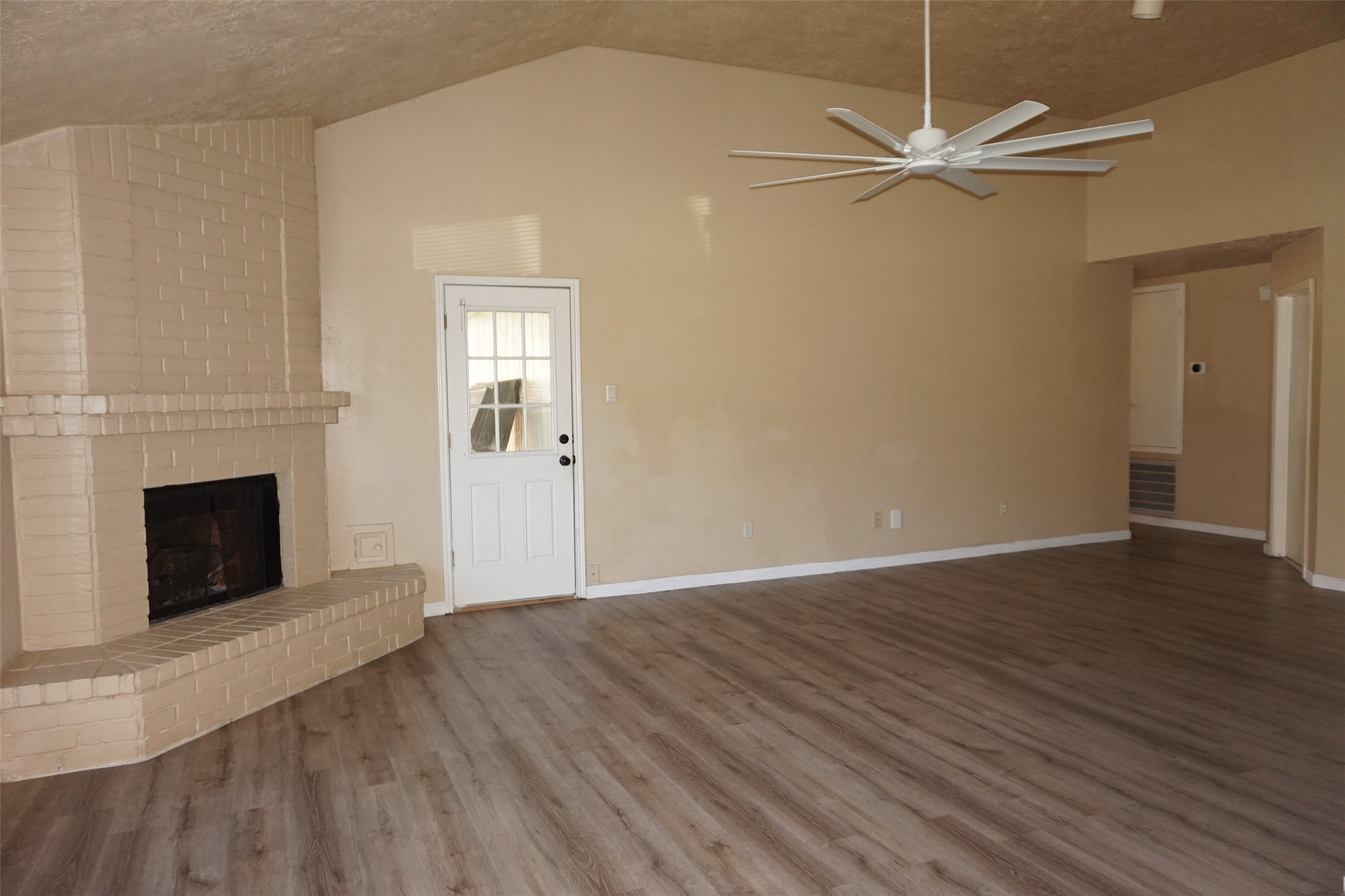6023 Woodmancote Drive Humble, TX 77346 - Photo 6 of 12 an empty room with wooden floor a ceiling fan a fireplace and windows