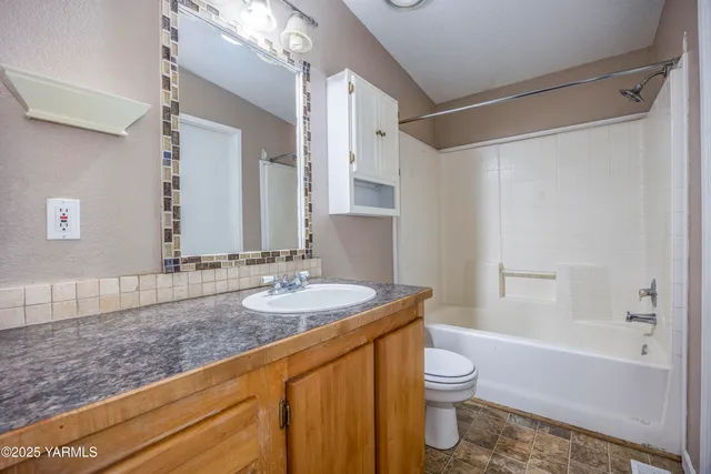 a bathroom with a granite countertop sink toilet a large mirror a bathtub and shower