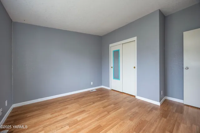 a view of empty room with wooden floor