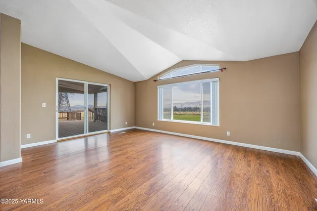 a view of an empty room with a window and wooden floor