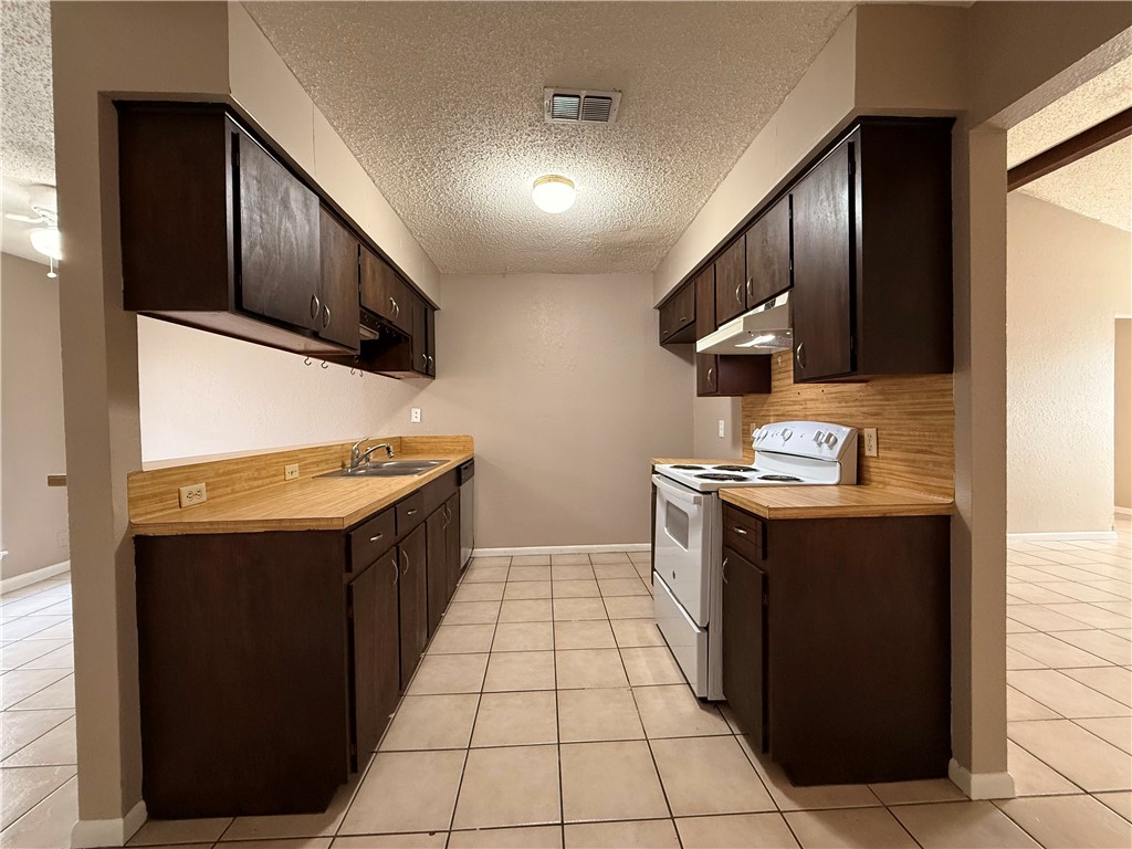 5018 Wingfoot Lane, Unit A Corpus Christi, TX 78413 - Photo 4 of 13 a kitchen with stainless steel appliances granite countertop a stove a sink and a refrigerator