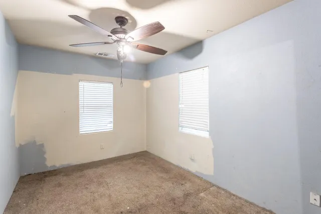 an empty room with a window and a fan