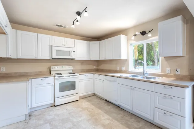a kitchen with cabinets appliances a sink and a window