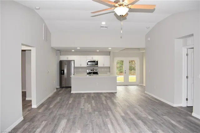 a living room with stainless steel appliances kitchen island hardwood floor and ceiling fan