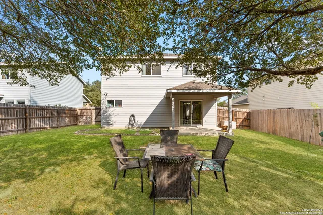 a view of a chair and table in backyard of the house