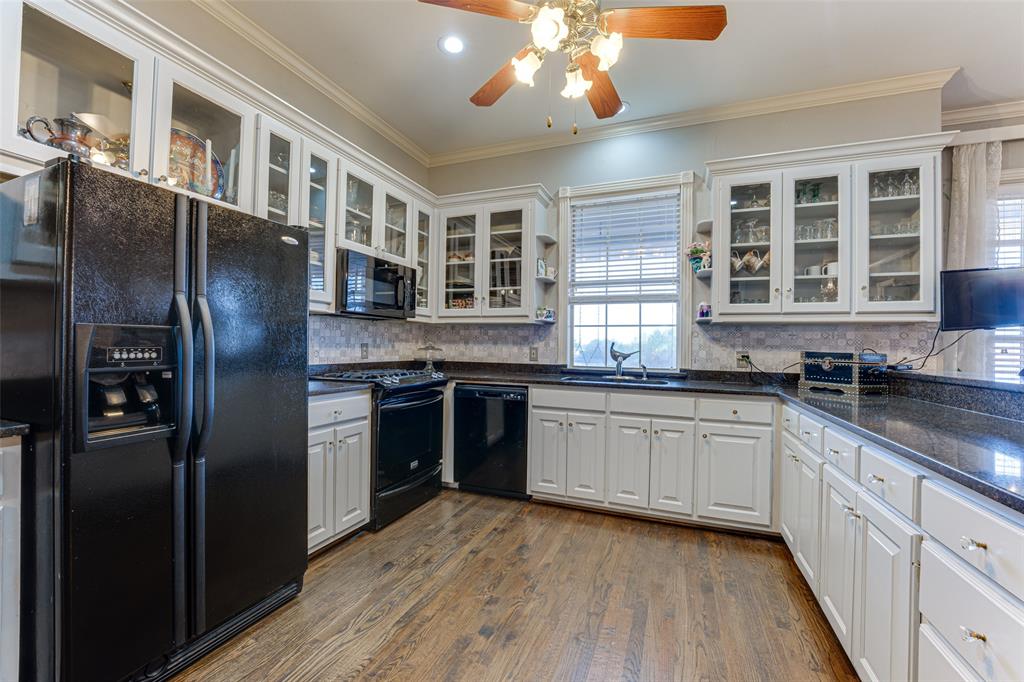 707 Cullins Road Rockwall, TX 75032 - Photo 27 of 35 a kitchen with stainless steel appliances granite countertop a refrigerator a sink dishwasher a stove and white countertops with wooden floor