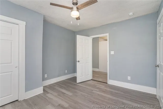 an empty room with wooden floor and ceiling fan