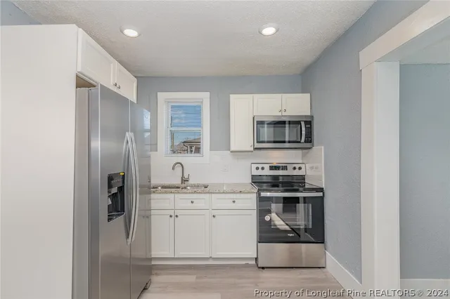 a kitchen with stainless steel appliances granite countertop a refrigerator stove and sink