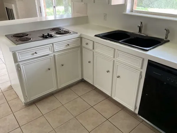 a kitchen with granite countertop white cabinets and black appliances