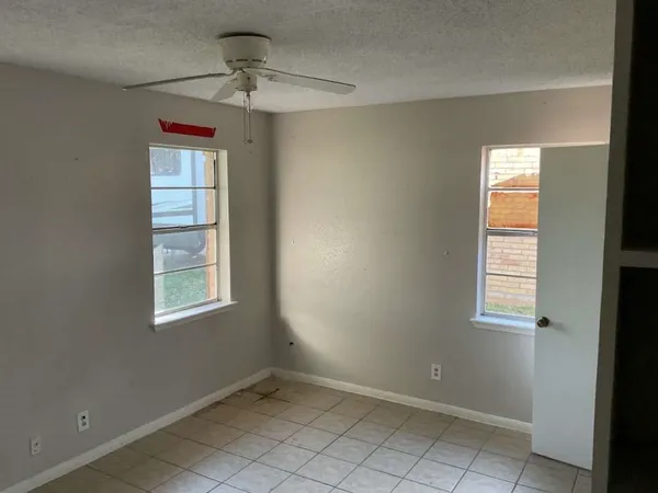 an empty room with windows and fan