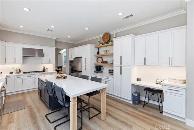 a kitchen with stainless steel appliances a white stove top oven a sink a chimney and cabinets