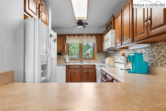 a kitchen with stainless steel appliances granite countertop a refrigerator a sink dishwasher a stove and white countertops with cabinets