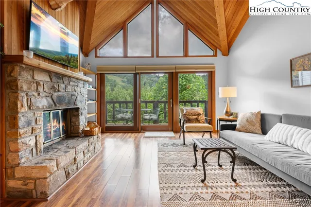 a living room with furniture a fireplace and a flat tv screen next to a large window